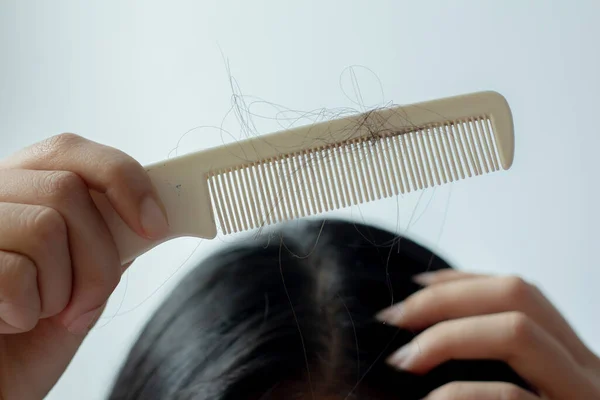 Young Asian woman with hair comb on white background, closeup problem hair.