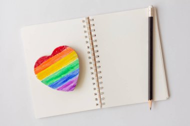 Ahşap masa arkasında gökkuşağı rengi kalp keskin. LGBT gurur simgesi.