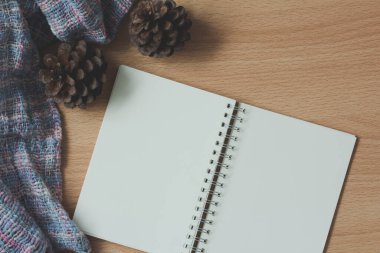Ahşap masanın üzerinde çam kozalağı olan boş kağıt defter. en üstteki görünüm.