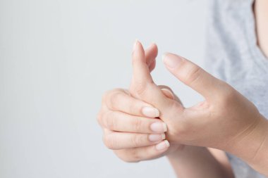 Ellerindeki acıdan muzdarip genç bir kadın ve acı çeken ellerine masaj yapıyor. Sağlık ve tıbbi konsept.