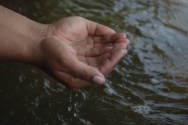 Water in male hand with surface river.World water or Environment day. Save water concept,