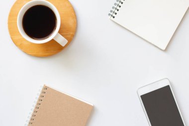 Not defteri ve akıllı telefonlu yaratıcı düz kahve. Kopya alanı olan beyaz masa üzerinde. Minimum.