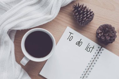 Ahşap masa üzerinde yapılacaklar listesi olan düz bir kahve fincanı ve defter. Sıcak bir sonbahar ve kış günü. planlama ve tasarım konsepti. 
