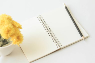 Beyaz arka planda sarı çiçekli boş bir defter..