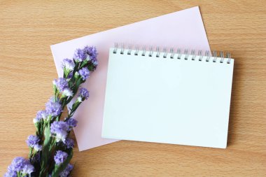 Ahşap masada mor çiçekli defter..
