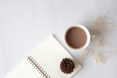 Beyaz fincan sıcak çikolata ve kuru çam kozalağı ile boş defterin en üst görüntüsü. Rahat masa..