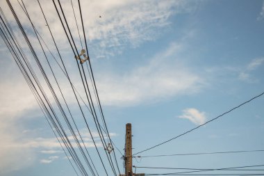 Mavi gökyüzü arka planında elektrik direği ve elektrik kablosu.