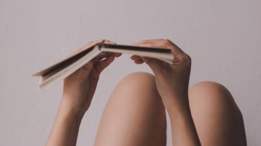 Yerde uzanmış kitap okuyan genç bir kadın. Yumuşak odak ve klasik ton.