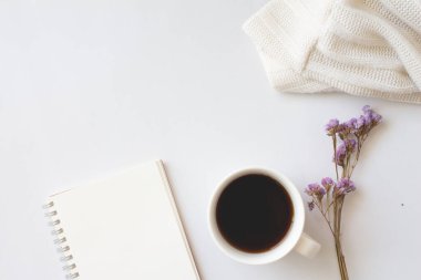 Tahta arka planda bir fincan kahve ve defter.