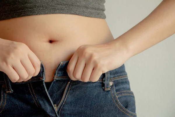 Fat woman wearing jeans.Hands unable to close the pants due to gaining fat on hips.Diet concept