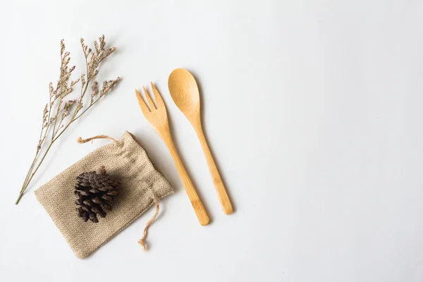 Flat lay of sustainable products, wooden spoon with natural sack bag and pine cone and dry flowers.on white background .ECO friendly and zero waste concept.