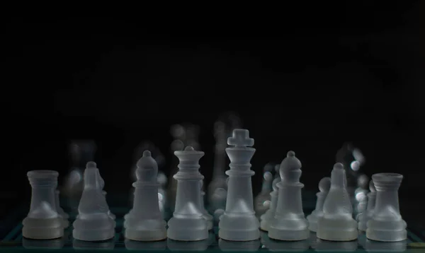 Siyah zemin üzerinde şeffaf ve mat parçalar olan cam satranç takımı