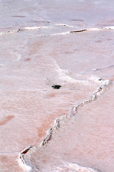 Abandoned salt industry. Pink salt lake. Salt mining. Industrial landscape and the beauty of nature. Shiny crystals of salt, reflection of clouds in the water. Salt crust marks