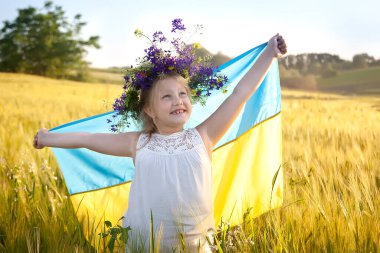 Mavi bir arka planda sarı ve mavi bir bayrak ve altın bir buğday tarlası olan mutlu bir Ukraynalı kız. Ukrayna 'nın Bağımsızlık Günü. Ukrayna Ulusal Bayrak Günü. Anayasa günü. sembol