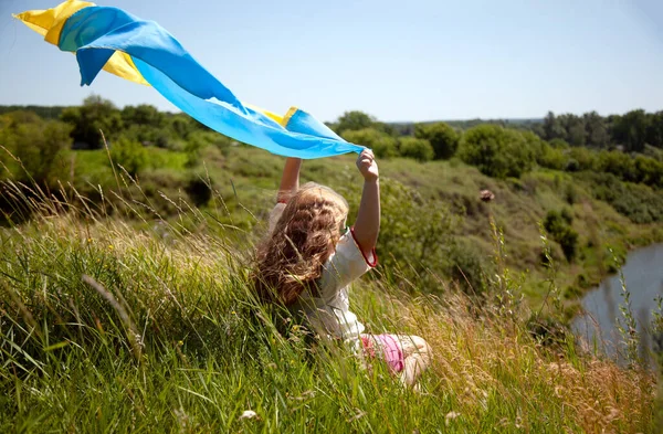 快乐的微笑着的乌克兰女孩在Vyshyvanka与黄色和蓝色的旗帜在高山上的田野和河流的背景 乌克兰独立日 乌克兰国旗日 — 图库照片
