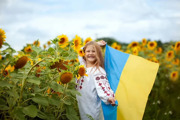 身穿传统绣花衬衫 手上拿着黄蓝色旗帜的乌克兰微笑女孩 她的手捧着一片向日葵 — 图库照片