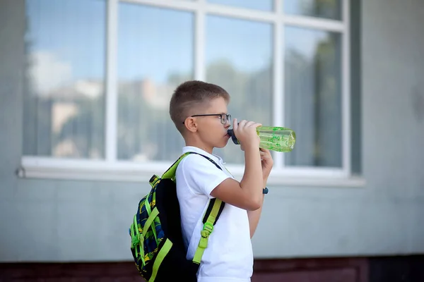 学校に戻る 男子生徒はリュックから水を１本取り出し 水を飲む 飲酒制度 新入生の皆さん — ストック写真