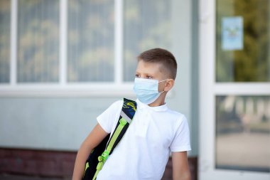 Back to school. Boy wearing mask and backpacks protect and safety from coronavirus. Child going school after pandemic over. Standing near school. Students ready for the new school year after quarantin clipart