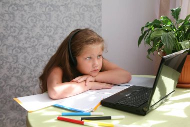 Odaklanmış çocuk yalnızlığı, kulaklık takmak kafede dizüstü bilgisayar kullanmak, notlar yazmak, kız öğrencilerin dil öğrenmesi, online webinar izlemek, evde eğitim, e-öğrenim konsepti.