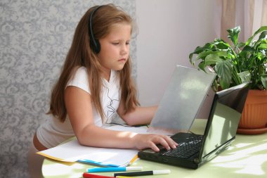 Odaklanmış çocuk yalnızlığı, kulaklık takmak kafede dizüstü bilgisayar kullanmak, notlar yazmak, kız öğrencilerin dil öğrenmesi, online webinar izlemek, evde eğitim, e-öğrenim konsepti.