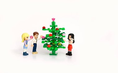 Kyiv, Ukrayna - 25 Eylül 2020: Lego minyatürleri - İki kız ve bir erkek arkadaş yılbaşı ağacı Yeni Yıl Lego konseptini dekore ediyorlar