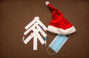 Noel yassı. Tıbbi spatulalardan yapılmış Noel ağacı. Test tüpleri, Noel Baba şapkası ve tıbbi maskeyle süslenmiş. Noel arkaplanı. Koronavirüs sırasında yeni yıl