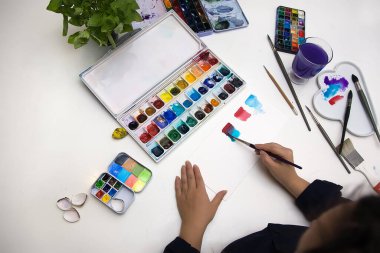 Kız suluboya resim yapıyor. Sanatçılar için hobiler, eğlence, yaratıcı düşünme ürünleri. Sanat eserleri yaratıcılık konsepti, su kolajı. 