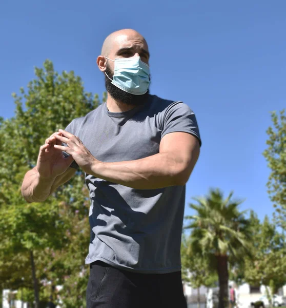 Spor salonundaki adam halka açık bir parkta esneyip maske takıyor.