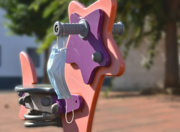 Halk parkında oyuncak attan sallanan yüz maskesi çocuklar için.