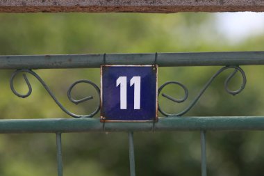 Eski model, kare, paslı, paslı bir plaka. Adres numarası da var. Yaklaş, marka..