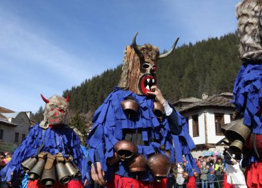 Shiroka laka, Bulgaristan - 1 Mart 2020: Bulgaristan 'ın Shiroka laka kentinde düzenlenen Maskeli Balo Festivali' nde maskeli insanlar dans ediyor ve kötü ruhları korkutmak için gösteri yapıyorlar.