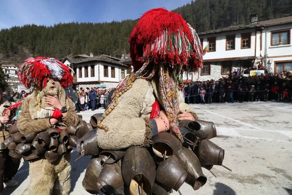 Shiroka laka, Bulgaristan - 1 Mart 2020: Bulgaristan 'ın Shiroka laka kentinde düzenlenen Maskeli Balo Festivali' nde maskeli insanlar dans ediyor ve kötü ruhları korkutmak için gösteri yapıyorlar.
