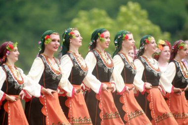 Varvara, Bulgaristan - 5 Mayıs 2015: Geleneksel kostümlü insanlar Varvara köyü yakınlarında bir çayır olan Bulgar horosuyla dans ediyorlar