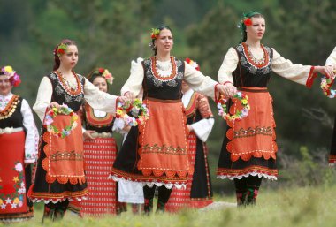 Varvara, Bulgaristan - 5 Mayıs 2015: Geleneksel kostümlü insanlar Varvara köyü yakınlarında bir çayır olan Bulgar horosuyla dans ediyorlar