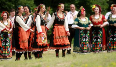 Varvara, Bulgaristan - 5 Mayıs 2015: Geleneksel kostümlü insanlar Varvara köyü yakınlarında bir çayır olan Bulgar horosuyla dans ediyorlar
