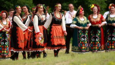 Varvara, Bulgaristan - 5 Mayıs 2015: Geleneksel kostümlü insanlar Varvara köyü yakınlarında bir çayır olan Bulgar horosuyla dans ediyorlar
