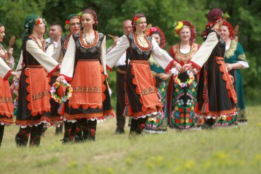 Varvara, Bulgaristan - 5 Mayıs 2015: Geleneksel kostümlü insanlar Varvara köyü yakınlarında bir çayır olan Bulgar horosuyla dans ediyorlar