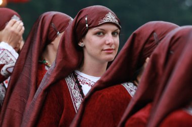 Koprivshtica, Bulgaria - August 7, 2010: People in traditional folk costume of The National Folklore Fair in Koprivshtica. The National Folklore Fair in Koprivshtica is entered in the UNESCO Register of the human intangible cultural heritage clipart