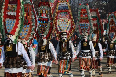 Pernik, Bulgaria - January 28, 2019: People with mask called Kukeri dance and perform to scare the evil spirits at the International Festival of Masquerade Games Surva in town Pernik, Bulgaria. clipart