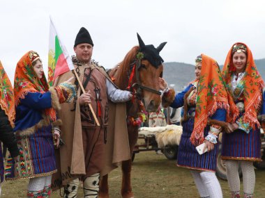 Velingrad, Bulgaristan - 24 Şubat 2018: Geleneksel kostümlü insanlar Velingrad yakınlarındaki bir çayır, At Paskalyası olarak da bilinen geleneksel Todorov Günü 'nde şarkı söyleyip dans ediyorlar.