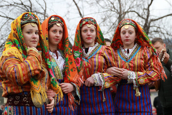 Velingrad, Bulgaria - February 24, 2018: People in traditional costumes sing and dance bulgarian horo a meadow near the ity of Velingrad, happening the traditional holiday "Todorov day" also known as Horse Easter