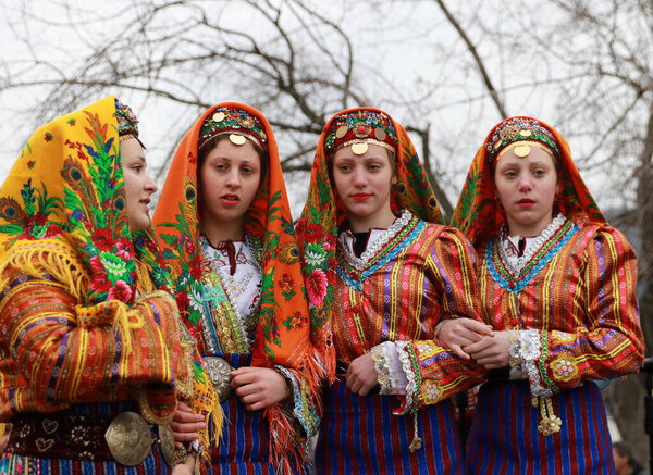 Velingrad, Bulgaria - February 24, 2018: People in traditional costumes sing and dance bulgarian horo a meadow near the ity of Velingrad, happening the traditional holiday "Todorov day" also known as Horse Easter