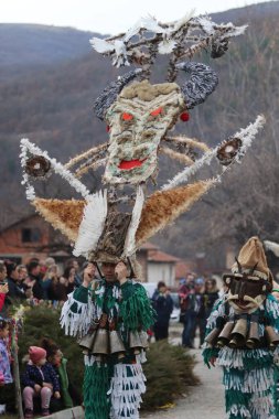 Zemen, Bulgaristan - 16 Mart 2019: Bulgaristan 'ın Zemen kentinde maskeli balo festivali Surva. Kukeri adındaki maskeli insanlar dans ediyor ve kötü ruhları korkutmak için gösteri yapıyorlar.