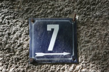 Eski model, kare, paslı, paslı bir plaka. Adres numarası da var. Yaklaş, marka.