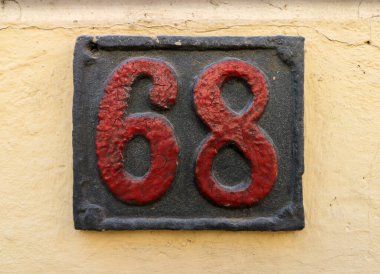 Eski model, kare, paslı, paslı bir plaka. Adres numarası da var. Yaklaş, marka.