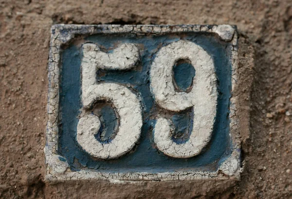 Eski model, kare, paslı, paslı bir plaka. Adres numarası da var. Yaklaş, marka.