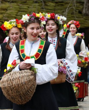 Gabrovo, Bulgarya- 8 Nisan 2017: Kızlar saçlarını renkli ve zengin bir şekilde dekore ediyor ve köyde şarkı söyleyip dans ediyorlar, bu şekilde evlenmeye hazır olduklarını gösteriyorlar.