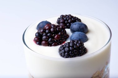 Bir bardak müsli, yoğurt, böğürtlen ve yabanmersini.