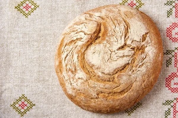 Keten bir masa örtüsünün üstünde bir somun ekmek.