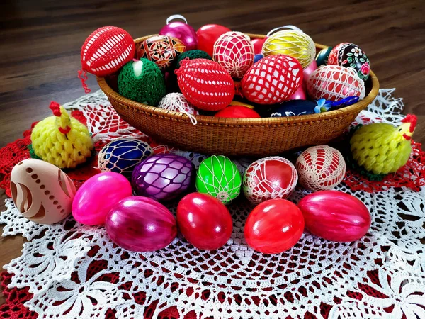 Örgü battaniyelere sarılmış sepetin içine boyanmış Paskalya yumurtaları, koyu bir arka plan.